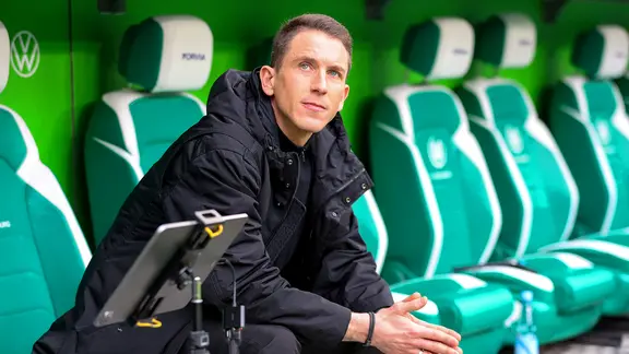 Daniel Bauer sits in the coaching bench of VfL Wolfsburg | IMAGO/Darius Simka Daniel Bauer sits in the coaching bench at VfL Wolfsburg