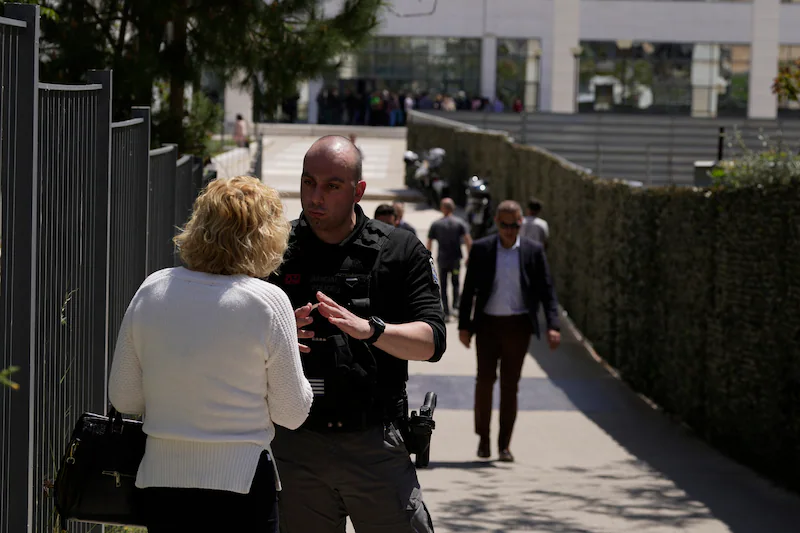A police officer speaks to a woman outside a courthouse after a gunman opened fire and injured several people in Athens.