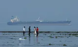 Tourists in the Narara Marine National Park in India with the MT Desert Kite oil tanker used for Russian oil in the background in the Arabian Sea.