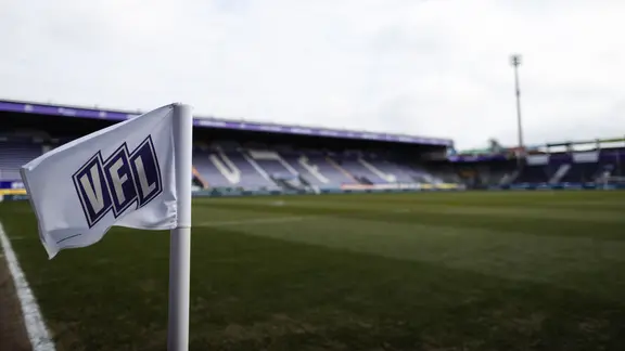 View of the field and the stands of the VfL stadium in Osnabrück, a small flag with a logo is waving in front.