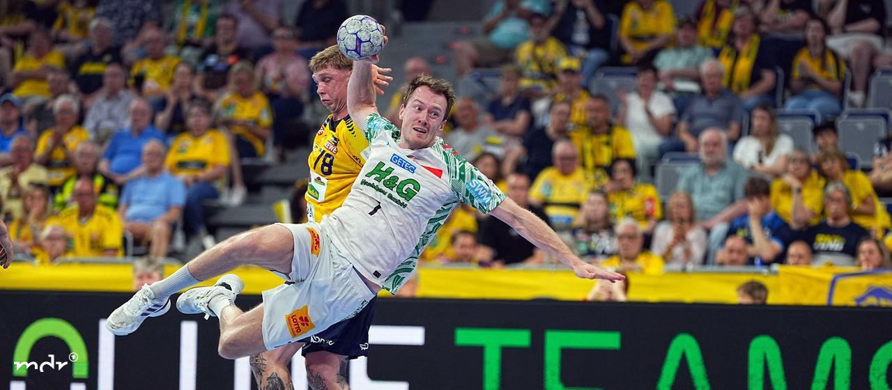 Felix Claar 7, SC Magdeburg, wearing the white SCM jersey, takes the shot while a Lions player in the yellow jersey 78 tries to block him. 