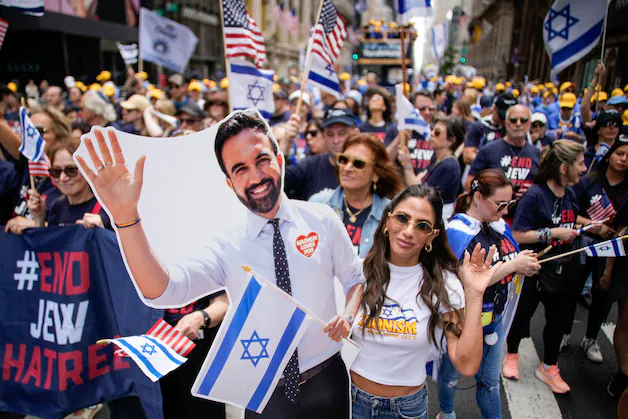 A woman at the parade with a cardboard sign depicting Mayor Mamdani. (31/05/26) 