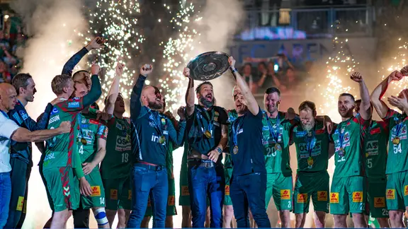 SCM trainer Bennet Wiegert holds up the championship trophy.