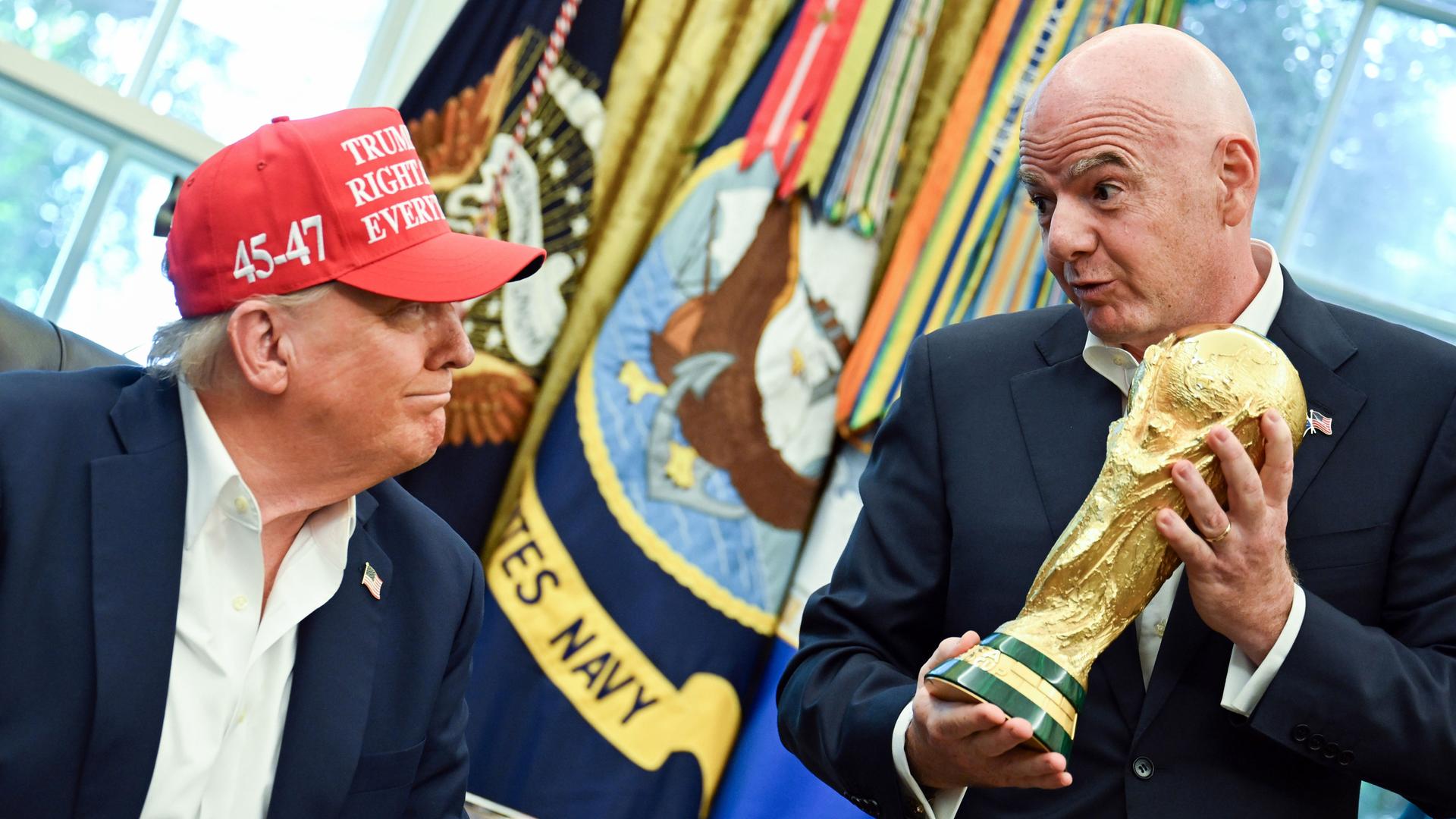 FIFA President Gianni Infantino holds the golden World Cup trophy in his hands in the Oval Offive and looks down on the sitting US President Donald Trump. He wears a red cap and grins back. FIFA President Gianni Infantino holds the golden World Cup trophy in his hands in the Oval Offive and looks down on the sitting US President Donald Trump. He wears a red cap and grins back.