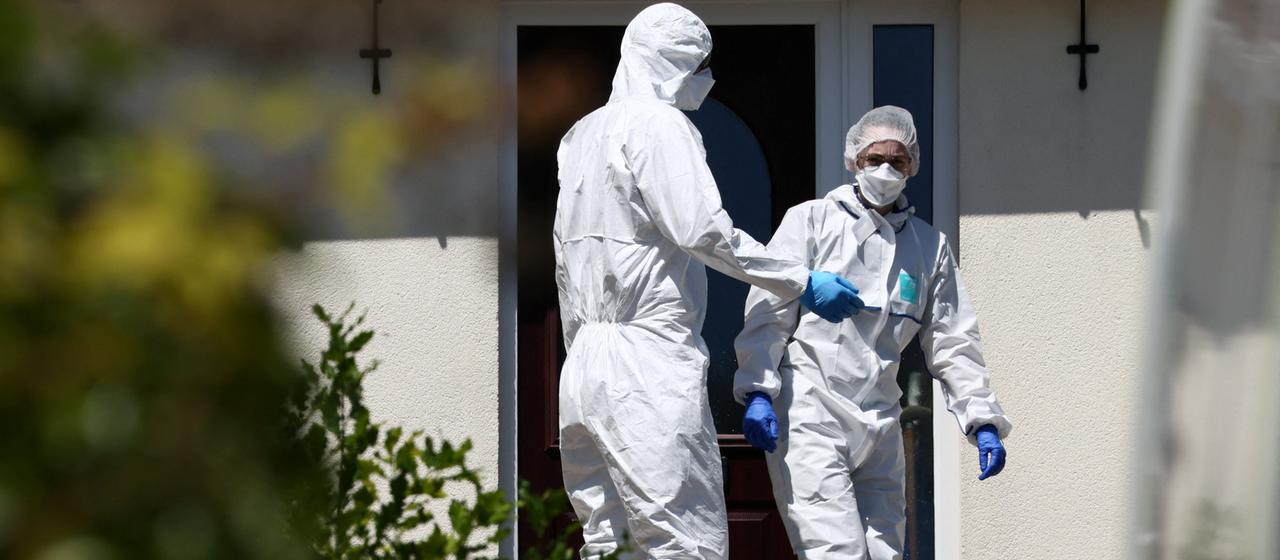Investigators in protective suits in front of Widdecombe's house
